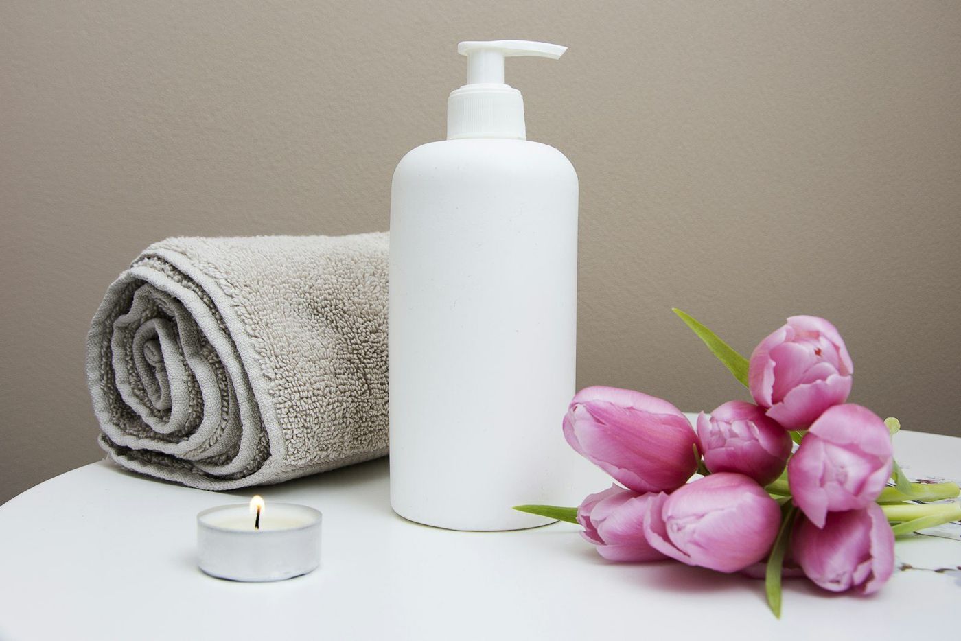 Imagen de referencia: toalla, loción y tulipanes en un ambiente de spa